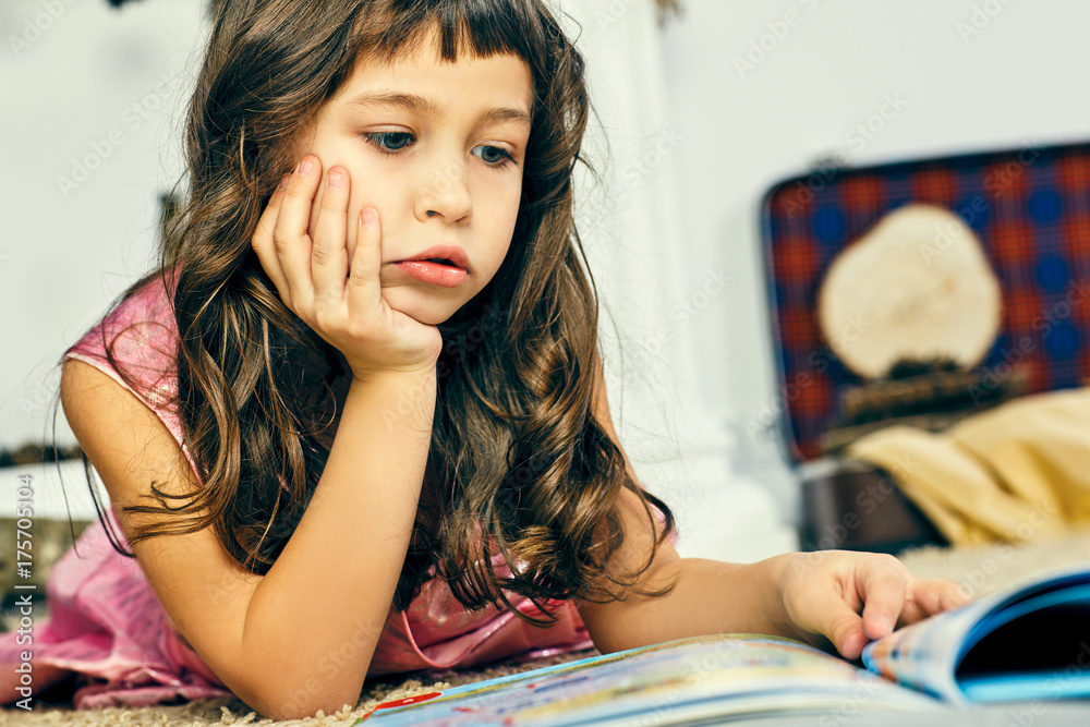 Little girl lying on the floor and reading an illustrated book. Little girl lying on the floor and reading an illustrated book.