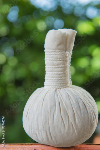 Spa massage compress balls, herbal ball on wooden table over bokeh from tree background, Thailand