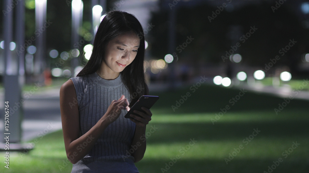 Fototapeta premium Woman using mobile phone in the city at night