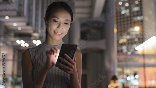 Woman looking at mobile phone in city at night
