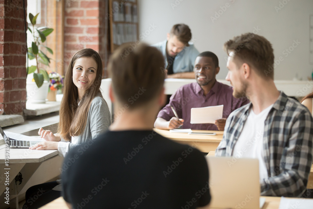 Female entrepreneur talking to one of coworkers in shared office. Team of colleagues communicate during workflow, employee inquiring about work strategy, specifics in workflow or casually chatting.