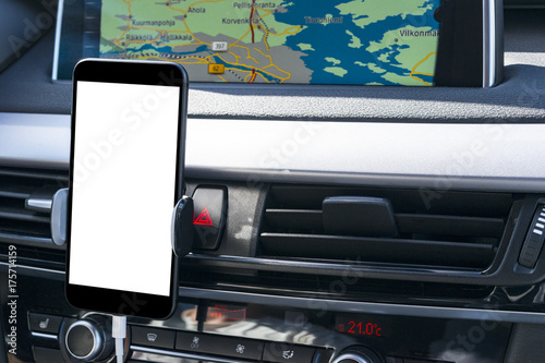 Smartphone in a car use for Navigate or GPS. Driving a car with Smartphone in holder. Mobile phone with isolatede white screen. Blank empty screen. Empty space for text. modern car interior details. photo