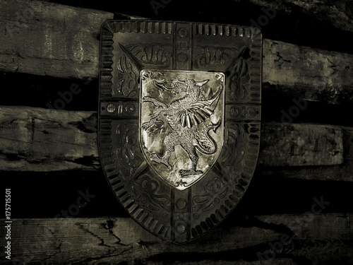 Old knight shield hangs on the wall in a castle. Black and white picture in vintage style