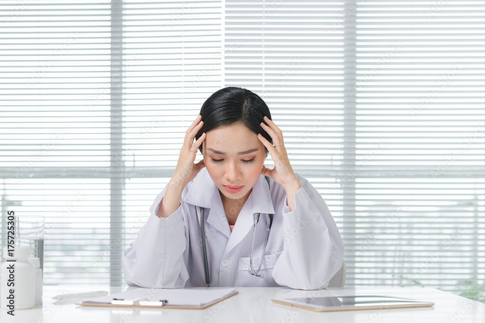 Frustration young female doctor sitting in her consulting room Frustration young female doctor sitting in her consulting room