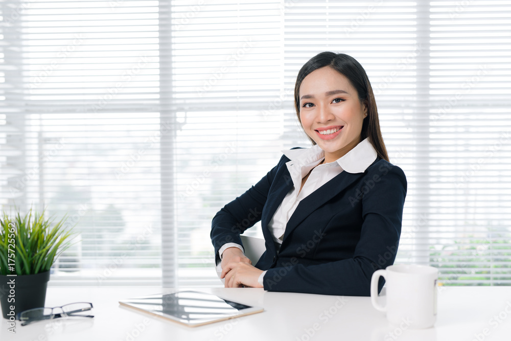Confident asian businesswoman sitting by desk in office Confident asian businesswoman sitting by desk in office