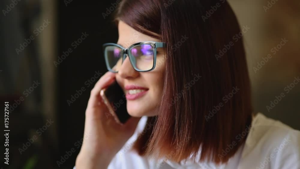 Very beautiful brunette with glasses razgovarivaet smiling using a mobile phone. Close-up. Very beautiful brunette with glasses razgovarivaet smiling using a mobile phone. Close-up.