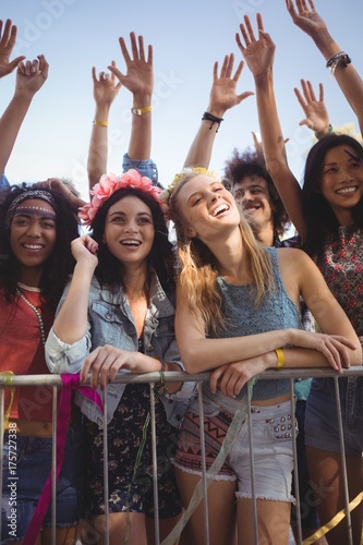 Fotografie Happy female friends standing by railing at music festival