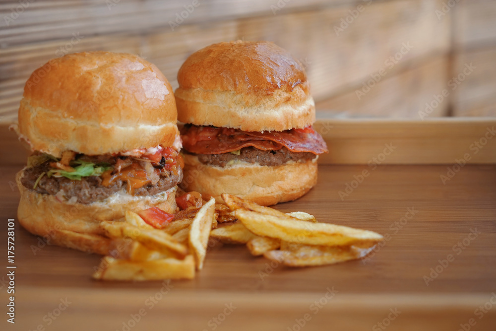 Tasty burgers with french fries on wooden tray
