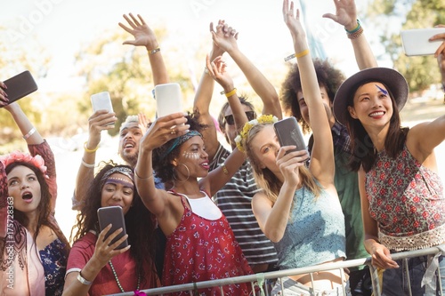 Smiling friends taking selfie through their mobile phones at