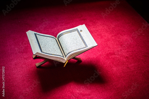 Holy book of Koran on stand on red carpet with vignetting affect.