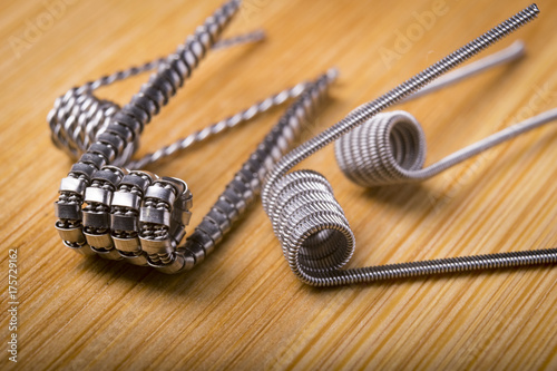 close up twisted coils for e cig or electronic cigarette for vape devices, RDA prebuild coil clapton over a wooden background. 