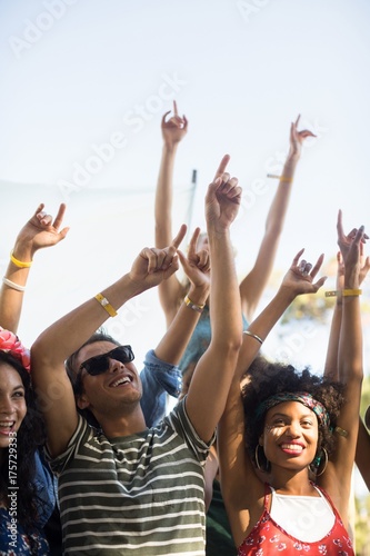 Happy fans dancing with arms raised during music festival