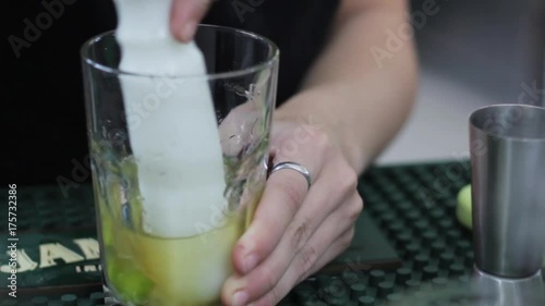A female bartender muddles a cocktail glass 