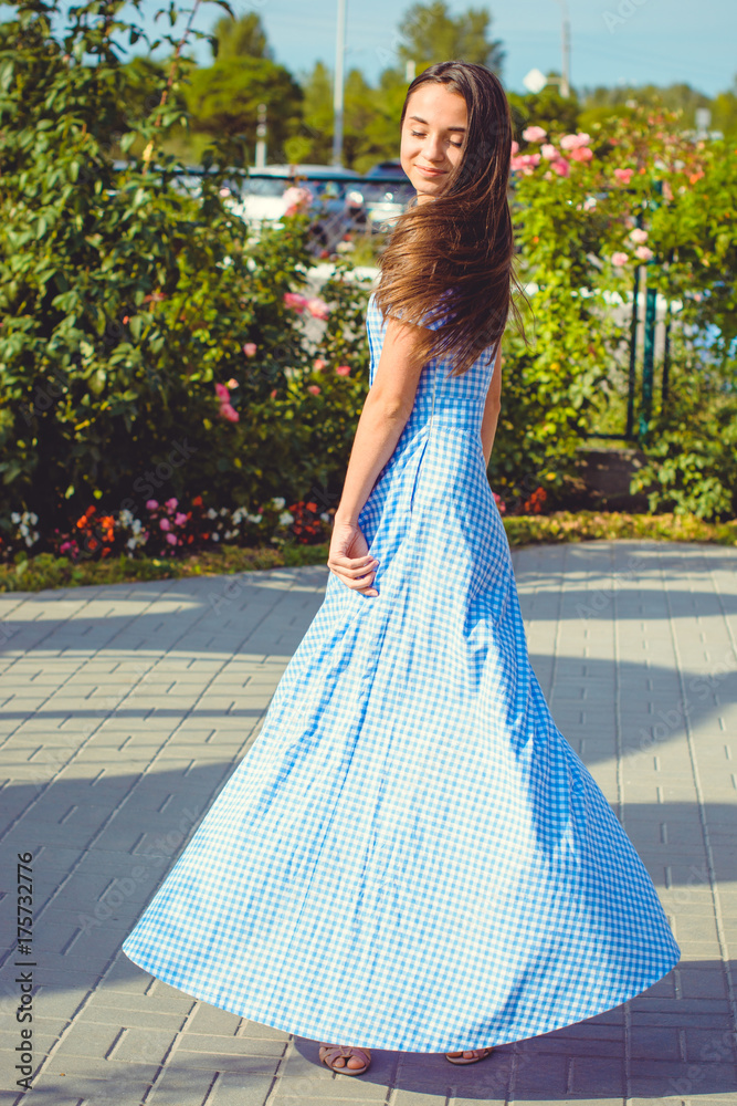 Beautiful young skinny girl walks around the city in a long dress in a cage and enjoys the day