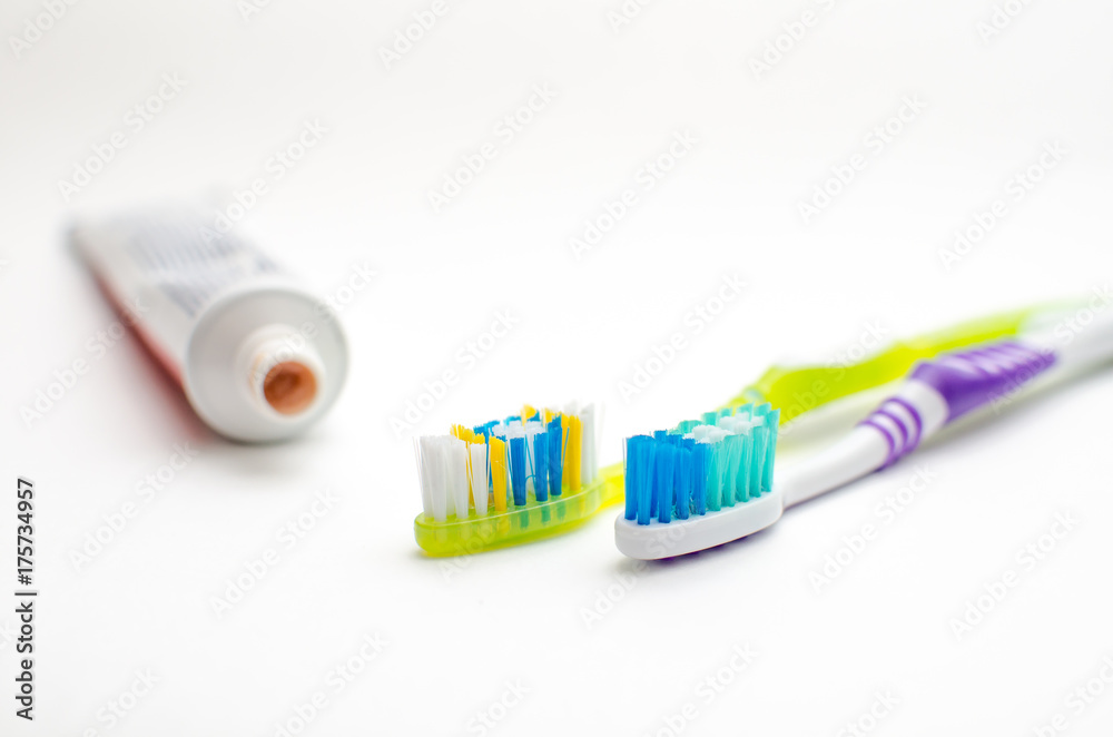 On a white background lies toothpaste and two brushes On a white background lies toothpaste and two brushes