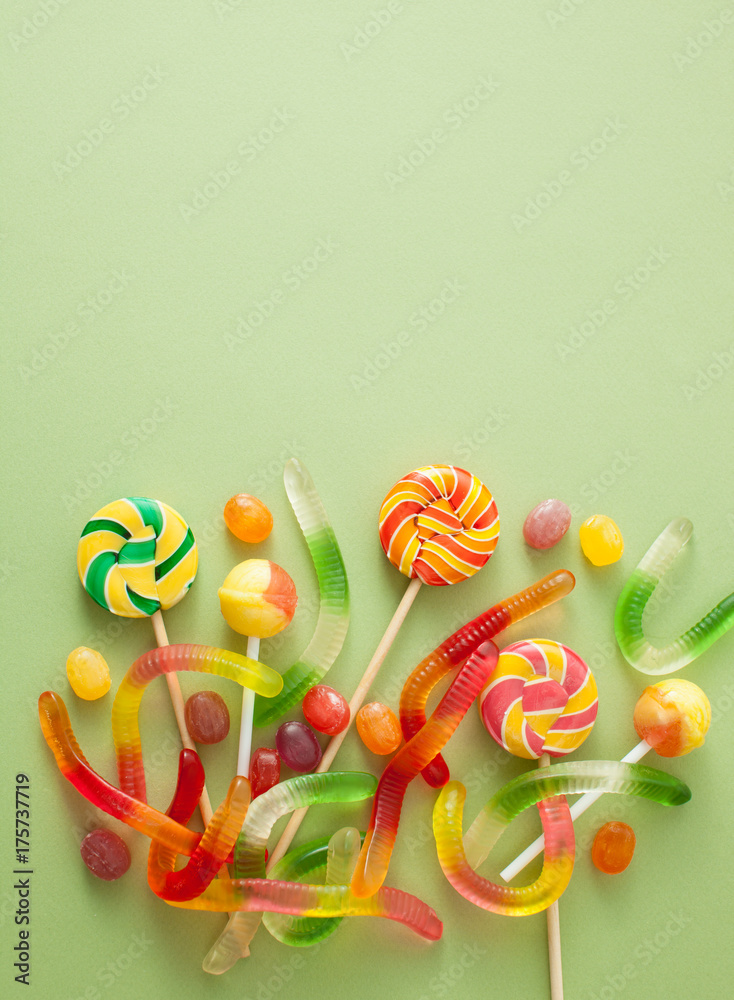 Colored candies for Halloween on a green background