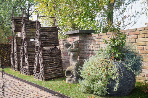 Sculpture of a mermaid, decorative way of wood storage and a large planter for decorating the garden photo