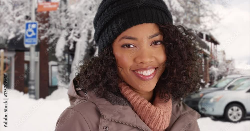 Close up of cute African American woman smiling at camera in snow covered town Close up of cute African American woman smiling at camera in snow covered town