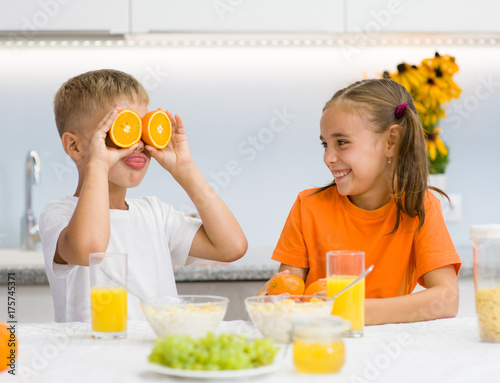 Brother laughs at his sister with orange before his eyes like in glasses © Ermolaev Alexandr