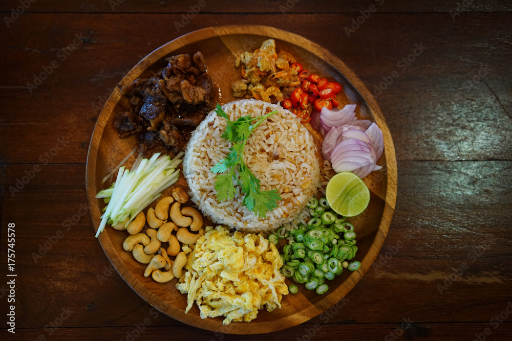 Kao Cluk Ka Pi or Mixed Cooked Rice with Shrimp Paste on the wooden round dish. Thai Traditional food. - obrazy, fototapety, plakaty 