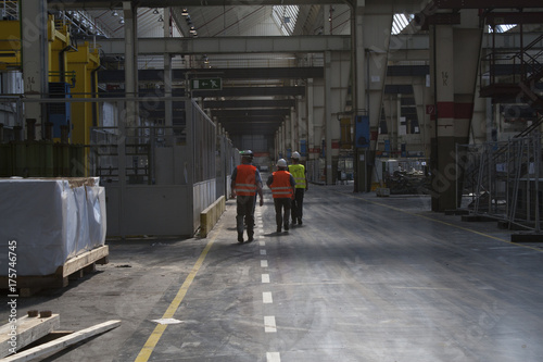 Arbeiter mit Warnwesten in einer Produktionshalle auf dem Weg zum Arbeitsplatz photo