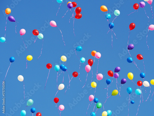 Multicolored balloons filled with helium in the blue cloudless sky. Flying multicolor balls
