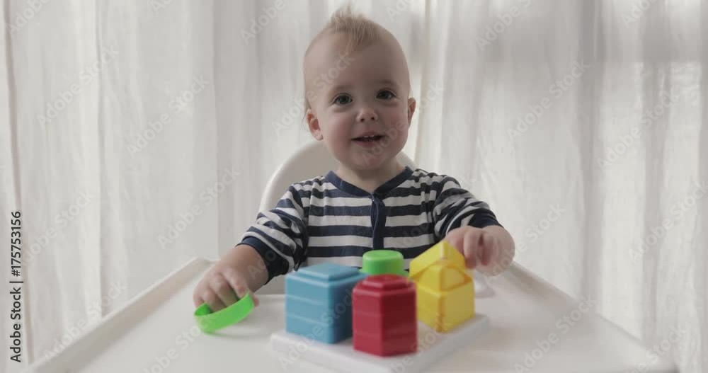 Baby boy plays educational toy sitting high chair Baby boy plays educational toy sitting high chair