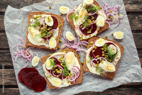 Danish open-face rye sandwich with quail eggs, beetroot, pickled onions and cucumbers drizzled with dill photo