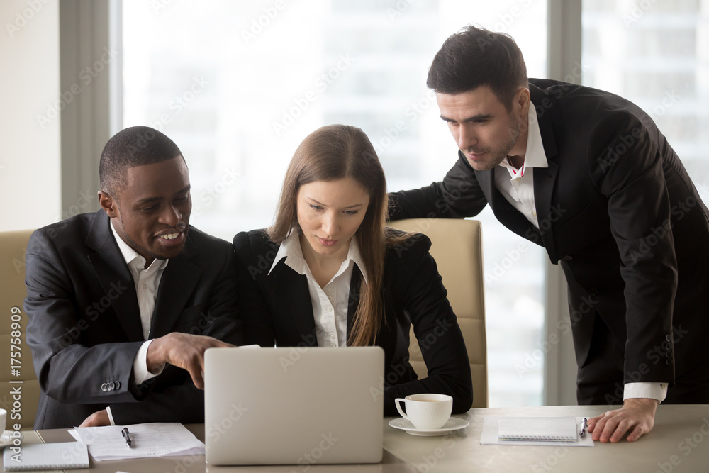 Φωτογραφία Group of millennial multinational business leaders discussing details of new project while working together on laptop in meeting room