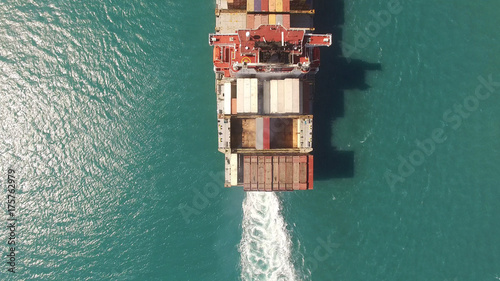 Huge large mega ULCV container ship sails on open water fully loaded with containers and cargo - aerial 4k view