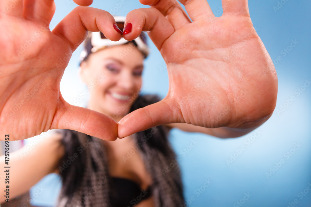 Woman in ski goggles making heart symbol fingers