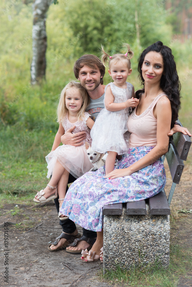 Beautiful young family with two daughters walking in the forest in summer