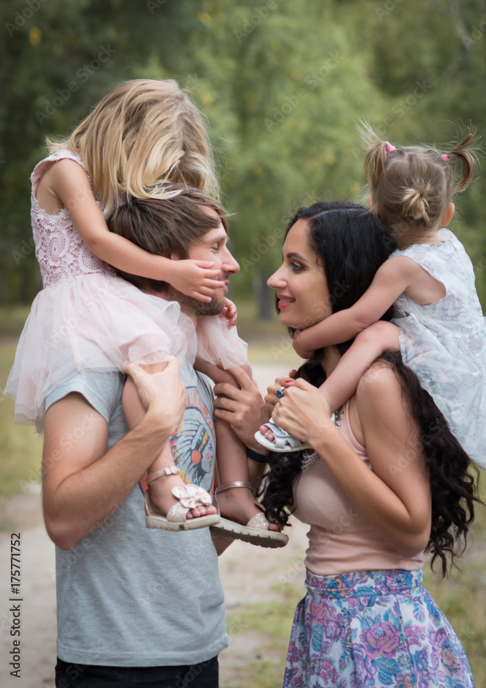 Obraz premium Beautiful young family with two daughters walking in the forest in summer