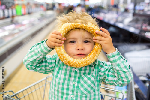 Happy children meal. For childish menu poster. Funny food story. Great choice of food. Cute funny boy in supermarket playing with rollaway bun. Snack in children's menu. Funny kid portrait gluten free