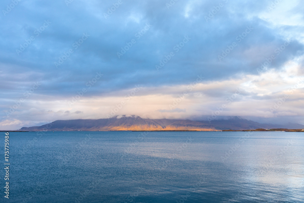 Embankment of Reykjavik with mountains and blue ocean.