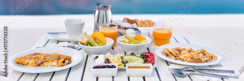 Breakfast brunch table fruits and omelettes for couple honeymoon at restaurant. Cruise vacation holiday travel destination, luxury hotel food panoramic crop.