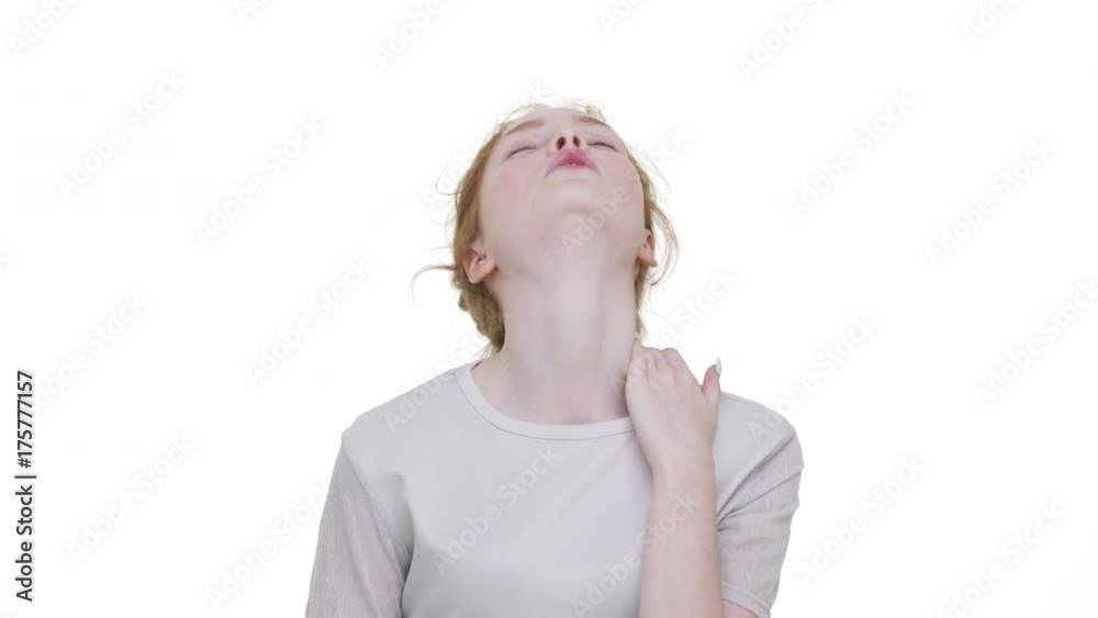portrait of tired red-haired woman in white shirt suffering from neck pain stretching turning it round looking strictly on camera over white background. Concept of emotions portrait of tired red-haired woman in white shirt suffering from neck pain stretching turning it round looking strictly on camera over white background. Concept of emotions