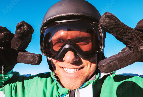 Skier dressed in ski helmet and ski goggles showing the two "victory" gestures portrait