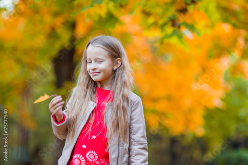 Portrait of adorable little girl with yellow trees background in fall