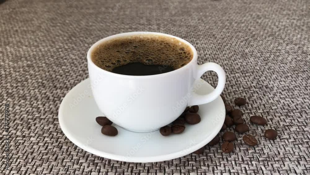 Cup hot drink with steam cinnamon sticks over black background White cup, Coffee granules brown roasted beans on sacking, hot coffee aroma spreads grain fragrant coffee brown Slow motion Cup hot drink with steam cinnamon sticks over black background White cup, Coffee granules brown roasted beans on sacking, hot coffee aroma spreads grain fragrant coffee brown Slow motion