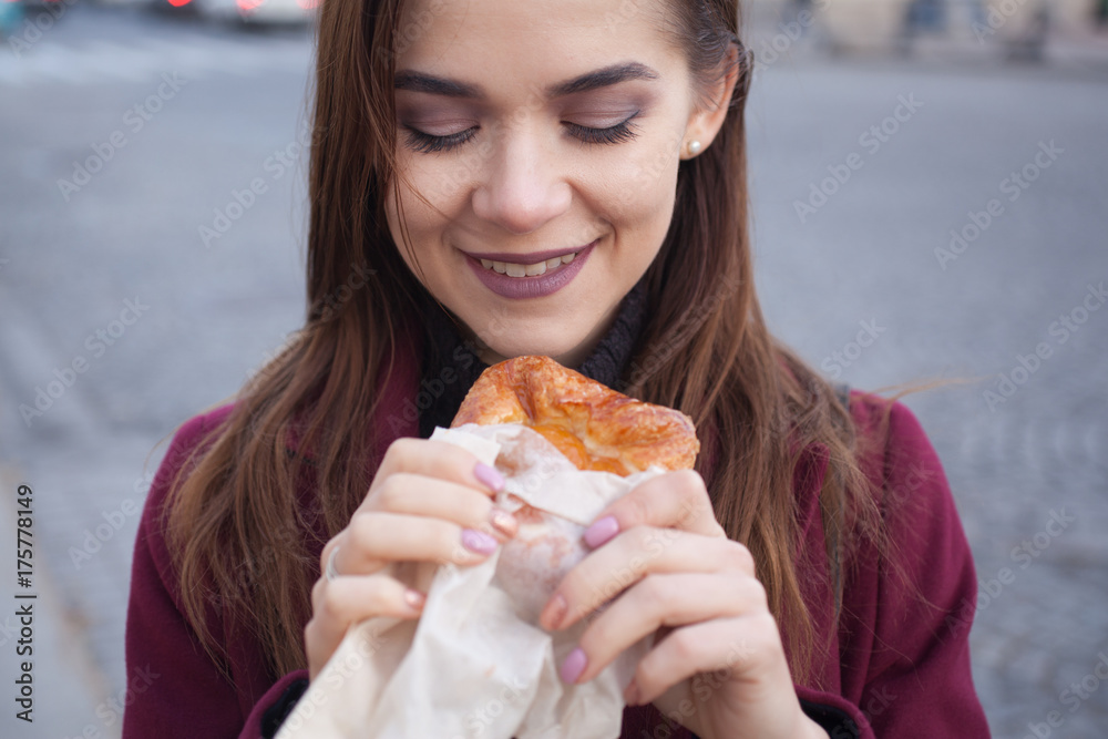 the girl on the street looking at the pastries in his hand and laughs the girl on the street looking at the pastries in his hand and laughs