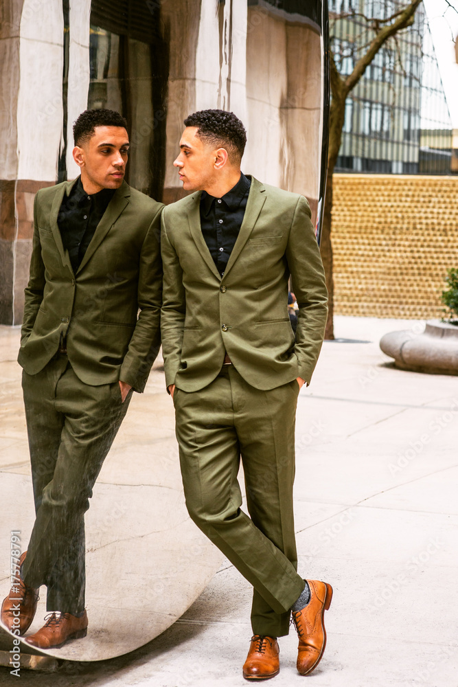 Fototapeta premium American Businessman looking at mirror, wearing green suit, black undershirt, brown leather shoes, standing against mirror, looking at reflection. Concept of self assured, self esteem, self checking..