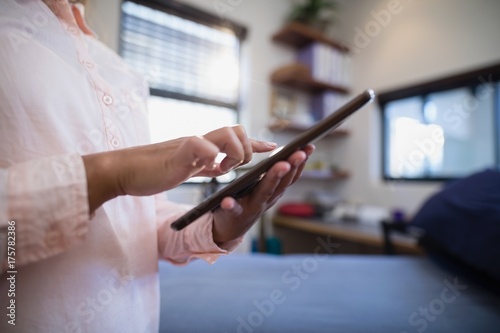 Midsection of female doctor using digital tablet