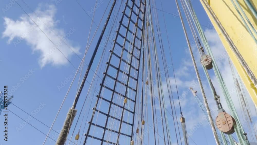 Masts of sail vessel on blue sky background. Rope ladder to the main mast of the ship. Masts of sail vessel on blue sky background. Rope ladder to the main mast of the ship.
