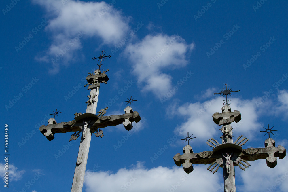 two wooden, old and ornamental crosses on a background of blue sky two wooden, old and ornamental crosses on a background of blue sky