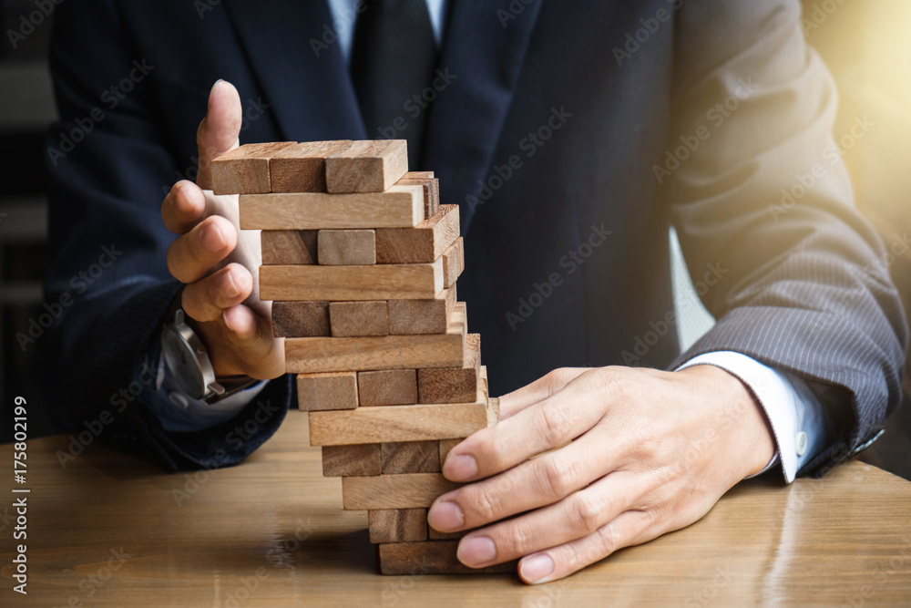 Alternative risk concept, plan and strategy in business, Young intelligent businessman raise the wood game, hands of executive sustain wood block on the tower, Collaborative management Alternative risk concept, plan and strategy in business, Young intelligent businessman raise the wood game, hands of executive sustain wood block on the tower, Collaborative management