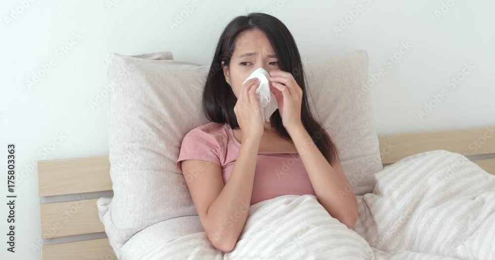 Woman feeling sick and sneezing on bed Woman feeling sick and sneezing on bed