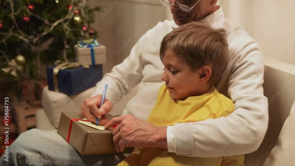 Pleasant aged man preparing Christmas presents with his grandson Pleasant aged man preparing Christmas presents with his grandson