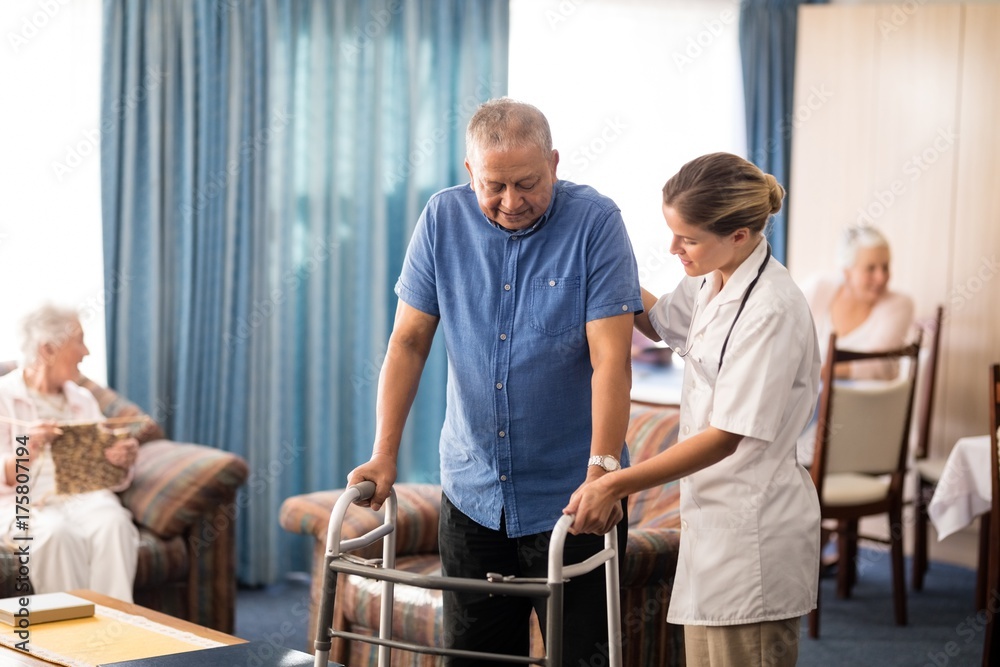 Fototapeta premium Female doctor assisting senior man walking with walker
