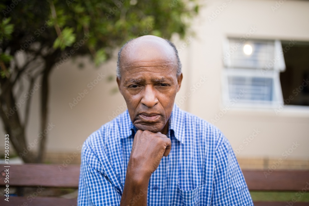 Depressed senior man sitting with hand on chin